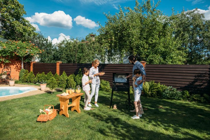 family having barbecue together on backyard on summer day