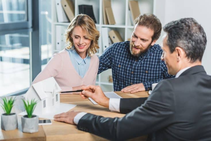 portrait of couple having meeting with realtor in real estate agency office